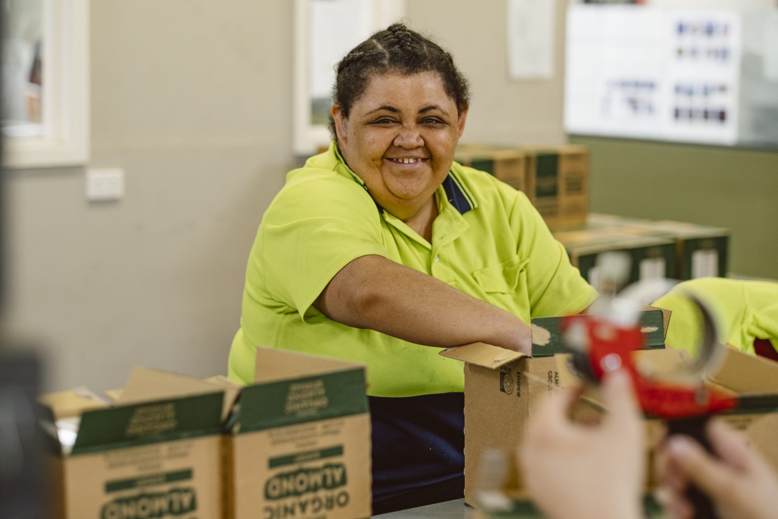 employee in high vis packing product into box while smiling